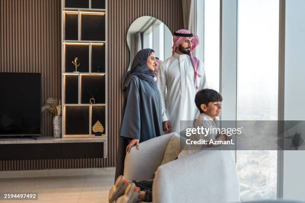 joyful arabic family appreciating riyadh skyline from modern home - arab culture stock pictures, royalty-free photos & images