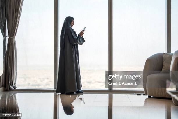 elegant arabic woman using smartphone with riyadh skyline - saudi arabia skyline stock pictures, royalty-free photos & images