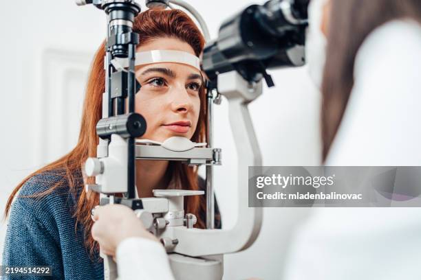 bella giovane donna che riceve un trattamento oftalmologico. medico oftalmologo che controlla la sua vista con attrezzature moderne. - miopia foto e immagini stock