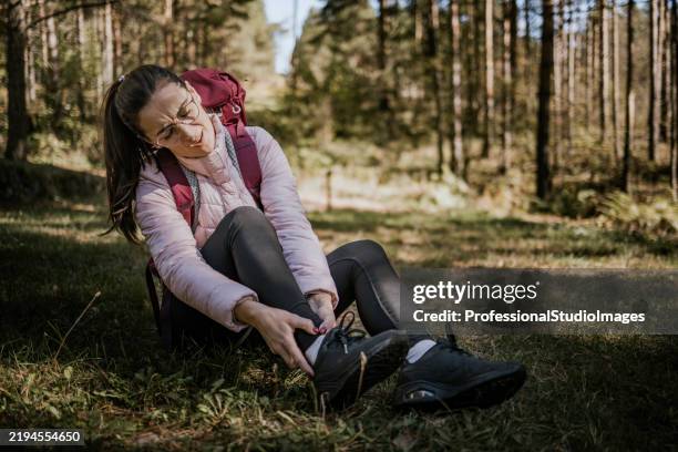 randonneur se reposant dans une forêt après s’être blessé à la cheville lors d’une chute sur un sentier difficile sous le soleil de l’après-midi - peine forte et dure photos et images de collection