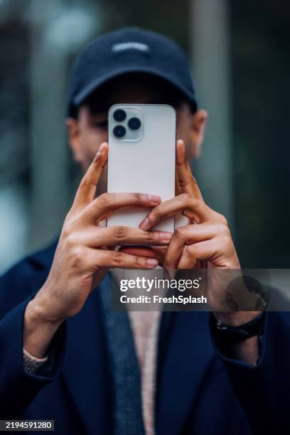 person, die ein foto mit dem smartphone im freien in lässigem outfit aufnimmt - gesicht verstecken stock-fotos und bilder