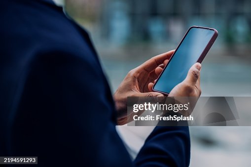 Close-Up of Hands Holding a Smartphone in an Urban Setting Close-Up of Hands Holding a Smartphone in an Urban Setting