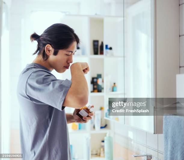 man testing fragrance at home in a modern bathroom environment - self improvement stock pictures, royalty-free photos & images