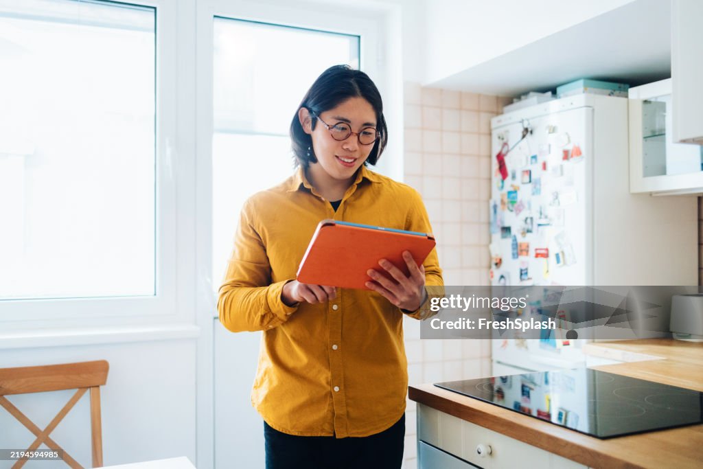 Man in Bright Kitchen Using Tablet and Smiling While Reading