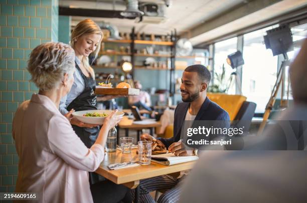 diverse business meeting in cozy bistro - waitress stock pictures, royalty-free photos & images