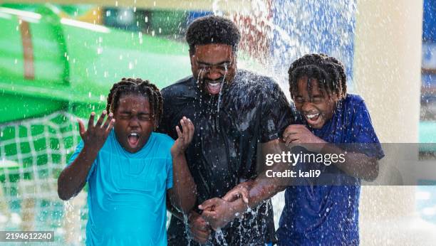 african-american father, boys get drenched at water park - water slide splash stock pictures, royalty-free photos & images