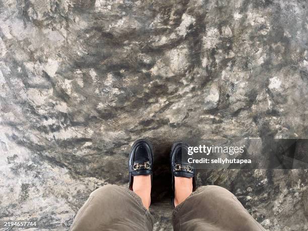 woman's leg in black loafer standing on a textured concrete floor - arte minimalista fotografías e imágenes de stock