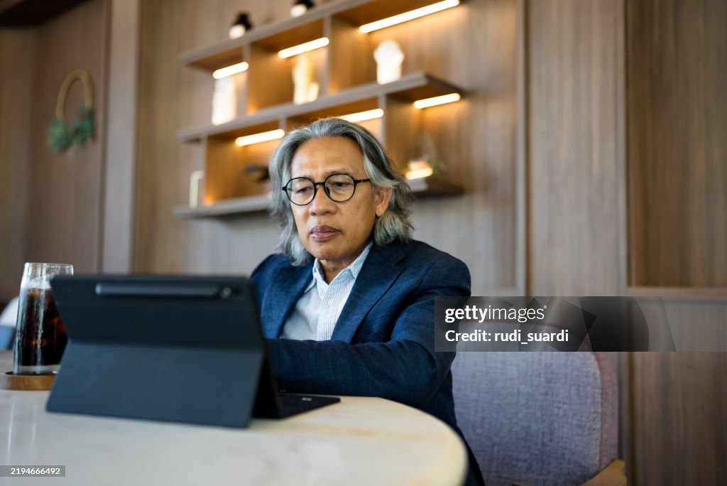 Senior Businessman using digital tablet in modern office