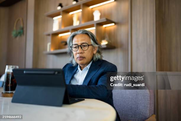 senior businessman using digital tablet in modern office - east asian ethnicity stock pictures, royalty-free photos & images