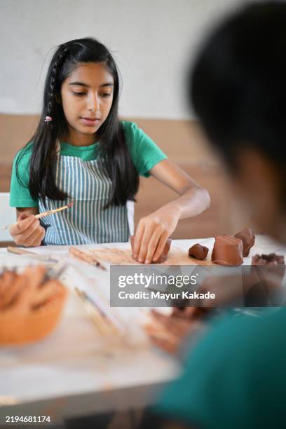 young girl immersed in crafting terra-cotta clay art with a brush - hobbies stock pictures, royalty-free photos & images