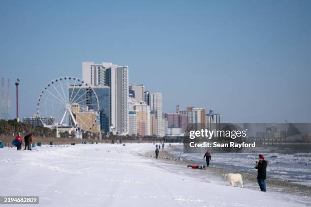 People explore snow on the beach on January 22, 2025 in Myrtle Beach, South Carolina. A winter storm brought heavy bands of snow and sleet to much of...
