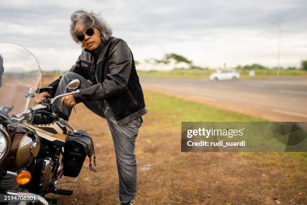a senior man getting on a motorcycle. - motorcycle live stock pictures, royalty-free photos & images