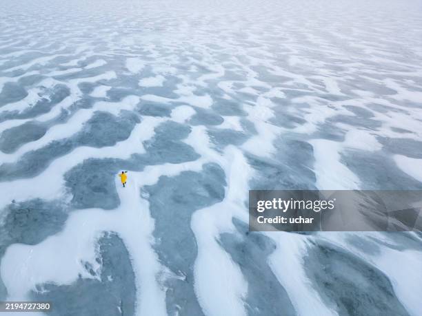 lone explorer walking on frozen lake covered with snow and ice - sneeuwjacht stockfoto's en -beelden
