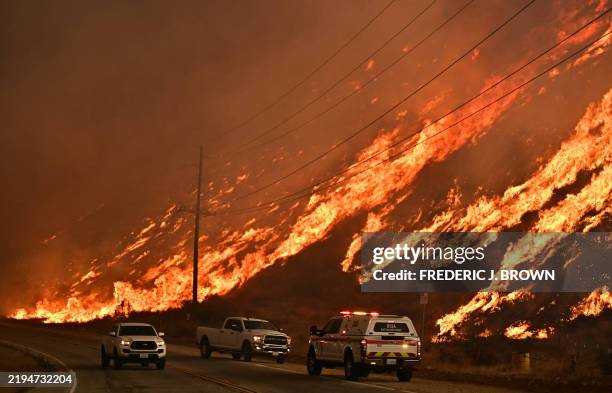 Emergency vehicles are on the side of the road as flames from the Hughes Fire race up the hill in Castaic, a northwestern neighborhood of Los...