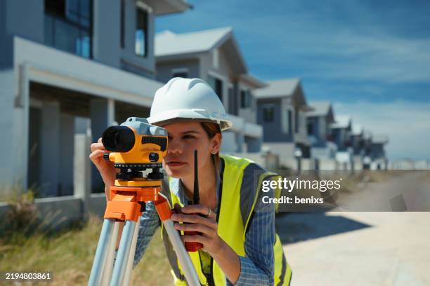 female surveyor using a theodolite to measure land at a residential construction site - land surveyor stock pictures, royalty-free photos & images
