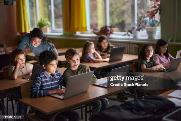 elementary students e-learning over laptops in the classroom. - classroom laptop stock pictures, royalty-free photos & images