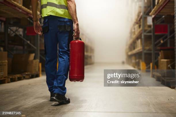 back view of manual worker with fire extinguisher in storage room. - fire extinguisher stock pictures, royalty-free photos & images