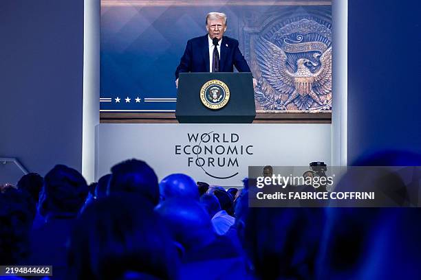 President Donald Trump is seen on a giant screen during his address by video conference at the World Economic Forum annual meeting in Davos on...
