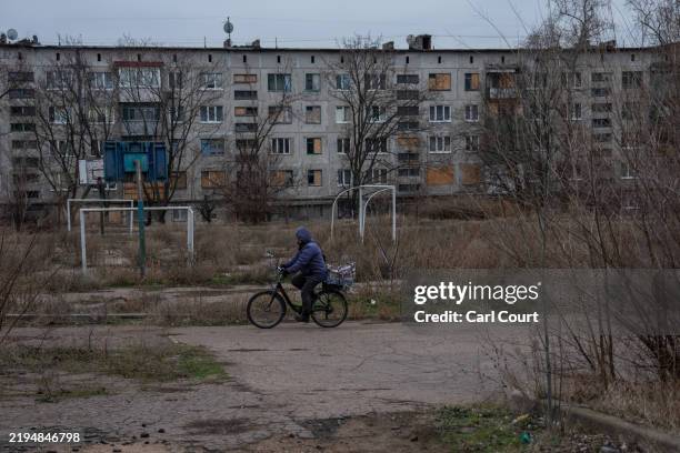 Man cycles past an overgrown sports pitch on January 23, 2025 in Kostyantynivka, Ukraine. Ukraine faces a pivotal moment in its war with Russia as...