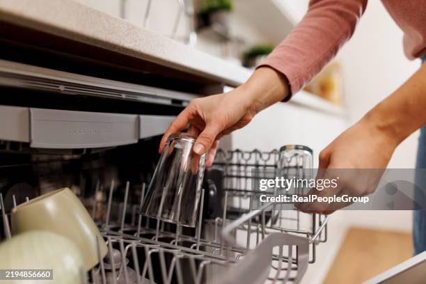 woman emptying the dishwasher in the kitchen - dishwasher stock pictures, royalty-free photos & images