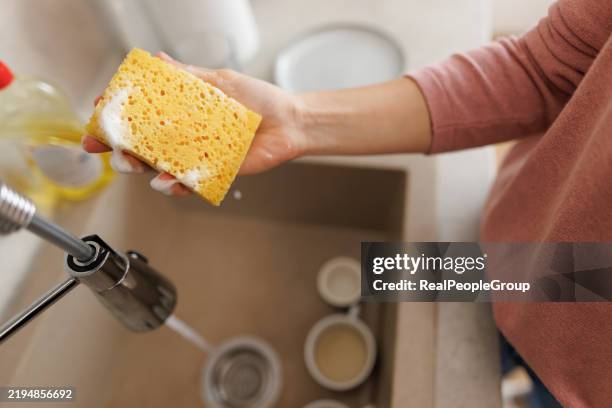 woman washing dishes in kitchen sink with sponge - cleaning sponge stock pictures, royalty-free photos & images
