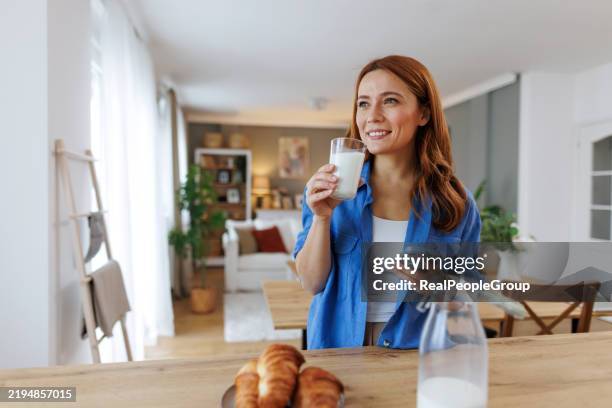 frau genießt das frühstück mit milch und croissants, während sie zu hause telefoniert - milch stock-fotos und bilder