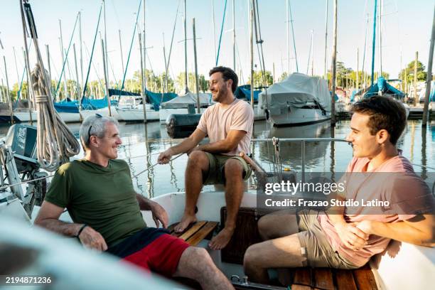young man talking to father and brother and preparing the sailboat during the travel - yachting stock pictures, royalty-free photos & images