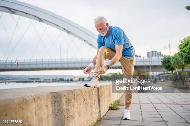 sporty senior man tying a shoelace outdoors - tying shoelace stock pictures, royalty-free photos & images