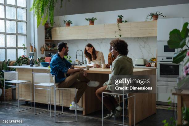 young adults enjoying coffee and conversation in modern kitchen - kitchen island stock pictures, royalty-free photos & images