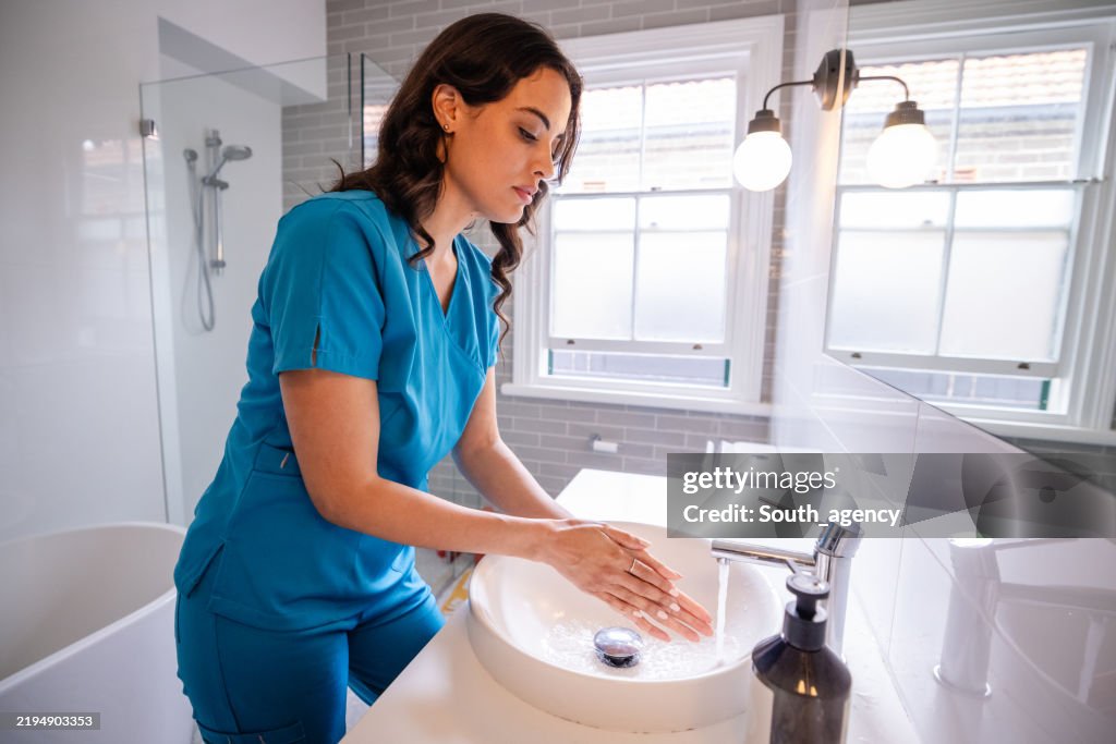 Focused hand washing by woman in medical uniform