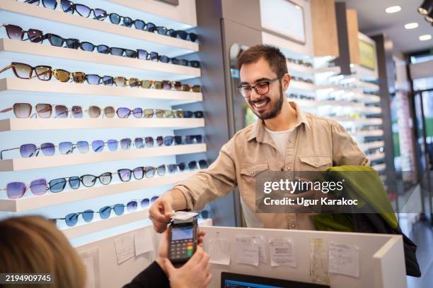 customer paying with credit card at the optic store. - optometry stock pictures, royalty-free photos & images