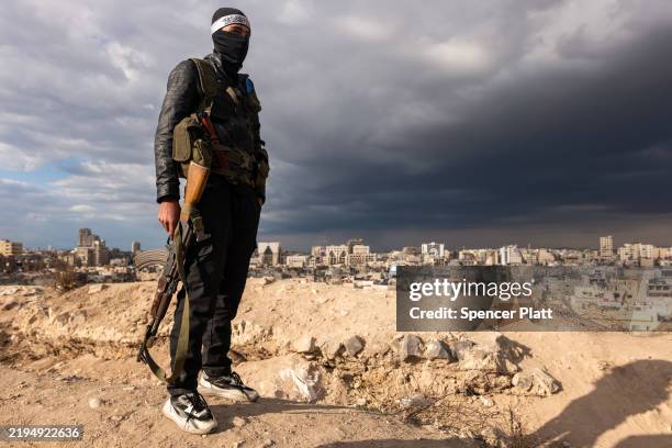 Fighter with Hayat Tahrir al-Sham, or HTS pauses with a Kalashnikov rifle while standing above the city of Homs on January 20, 2025 in Homs, Syria....