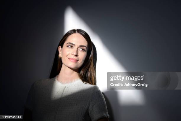 elegant businesswoman looking up and smiling with light and shadow on her face - high contrast stock pictures, royalty-free photos & images