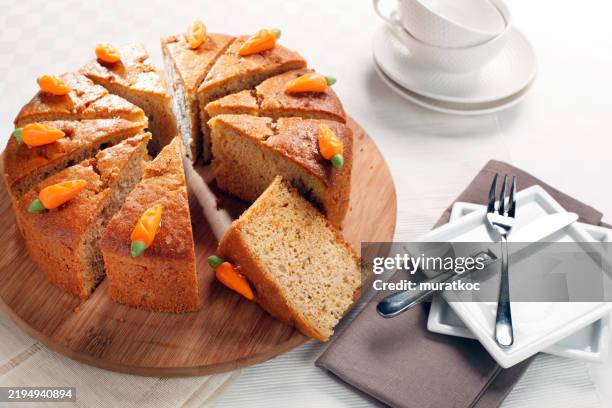 carrot cake with sugar made carrot decorations, sliced on a wooden service plate - carrot cake stock pictures, royalty-free photos & images