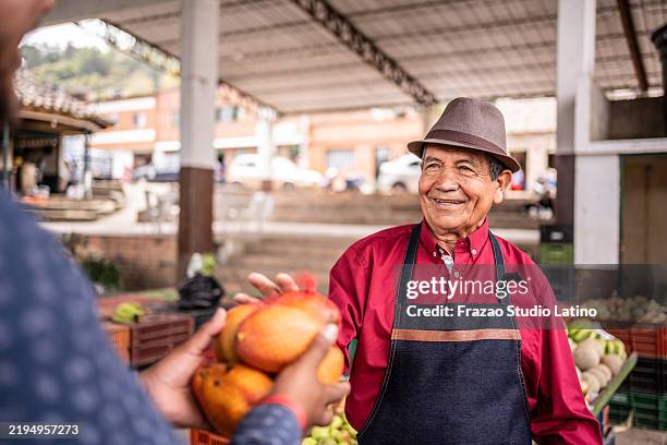 salesman attending customer on a farmer's market - mango fruit stock pictures, royalty-free photos & images