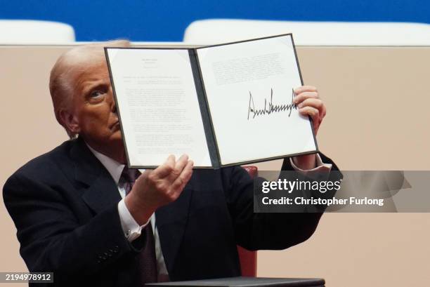President Donald Trump holds up an executive orders after signing it during an indoor inauguration parade at Capital One Arena on January 20, 2025 in...