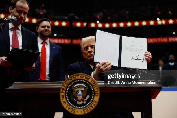 President Donald Trump holds up an executive order after signing it during an indoor inauguration parade at Capital One Arena on January 20, 2025 in...