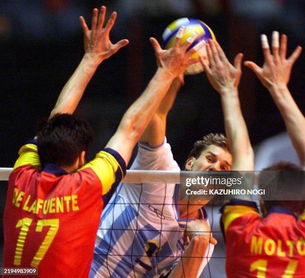 Argentina volleyball team captain Marcoa Milinkovic spikes the ball over Spanish players, Enrique De La Fuente and Jose Luis Molto , during the...