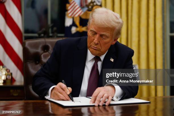 President Donald Trump signs executive orders in the Oval Office of the White House on January 20, 2025 in Washington, DC. Trump takes office for his...
