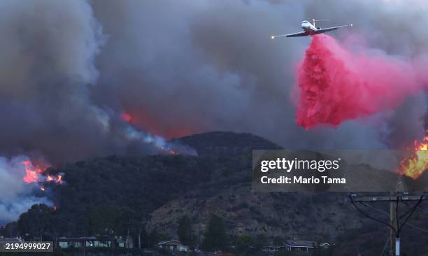 Firefighting aircraft drops the fire retardant Phos-Chek as the Palisades Fire burns amid a powerful windstorm on January 7, 2025 in Pacific...