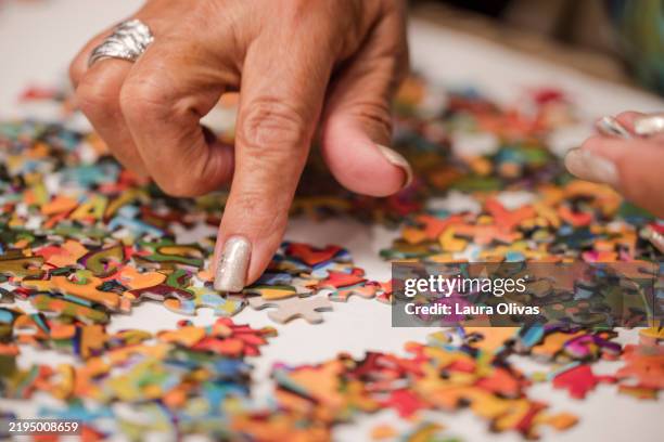 closeup of woman's hand touching puzzle pieces - legpuzzel stockfoto's en -beelden