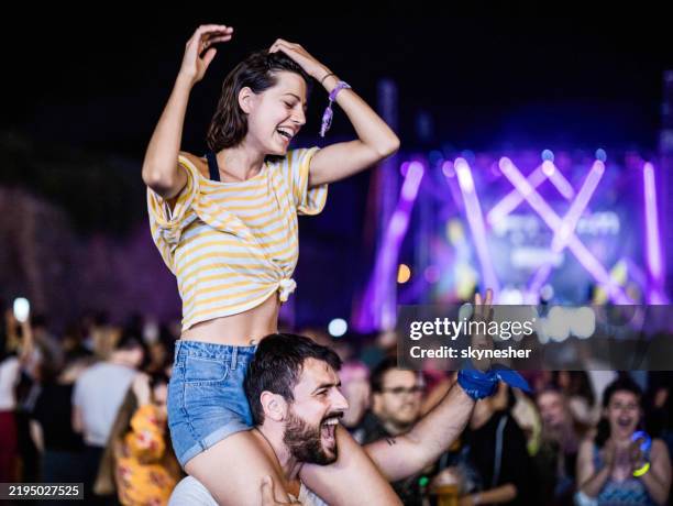 feliz pareja divirtiéndose en un festival de música por la noche. - llevar al hombro fotografías e imágenes de stock