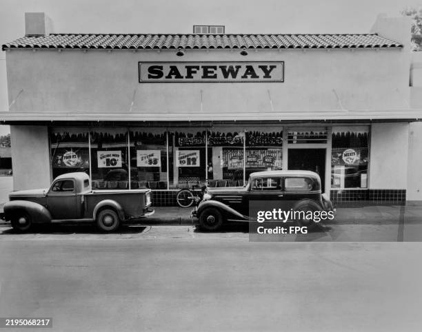 Willys-Overland Jeepster pickup truck and a Chevrolet Master parked outside a 'Safeway' store, with offers advertised in the store windows in...