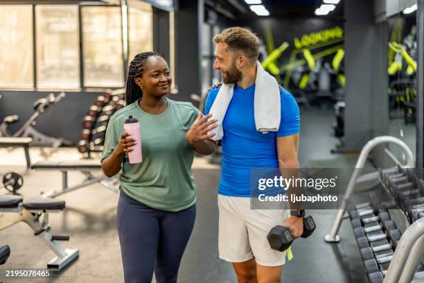 fitness companions sharing a moment in a modern gym environment - gym stock pictures, royalty-free photos & images