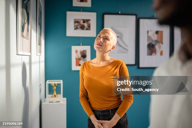 visitors engaging with contemporary artwork at a vibrant art exhibition in a gallery setting - espetáculo de arte imagens e fotografias de stock