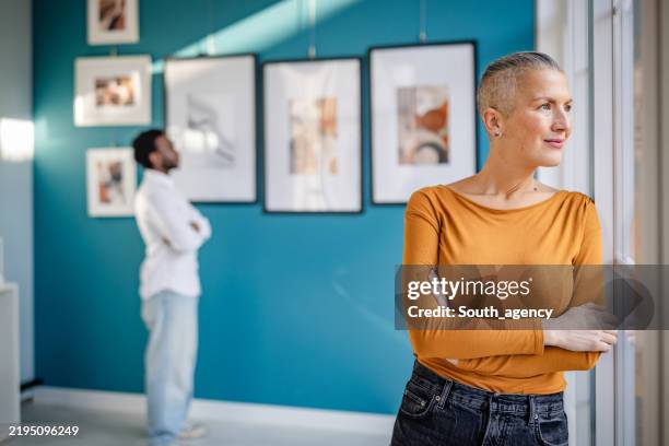 los visitantes interactúan con el arte contemporáneo en un entorno de galería vibrante durante una exposición - inauguración-de-galería fotografías e imágenes de stock