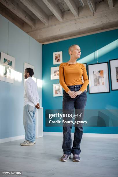 visitors admire contemporary art in a vibrant gallery setting while engaging in thoughtful observation - espetáculo de arte imagens e fotografias de stock