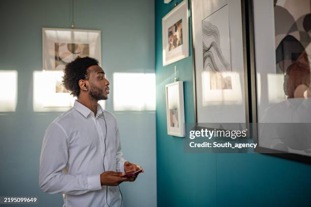 visitor admires modern art pieces at a contemporary gallery during a sunny afternoon - espetáculo de arte imagens e fotografias de stock