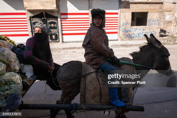 Children ride a donkey as they collect garbage in the city of Homs on January 21, 2025 in Homs, Syria. Homs, the country’s third-largest city, has a...