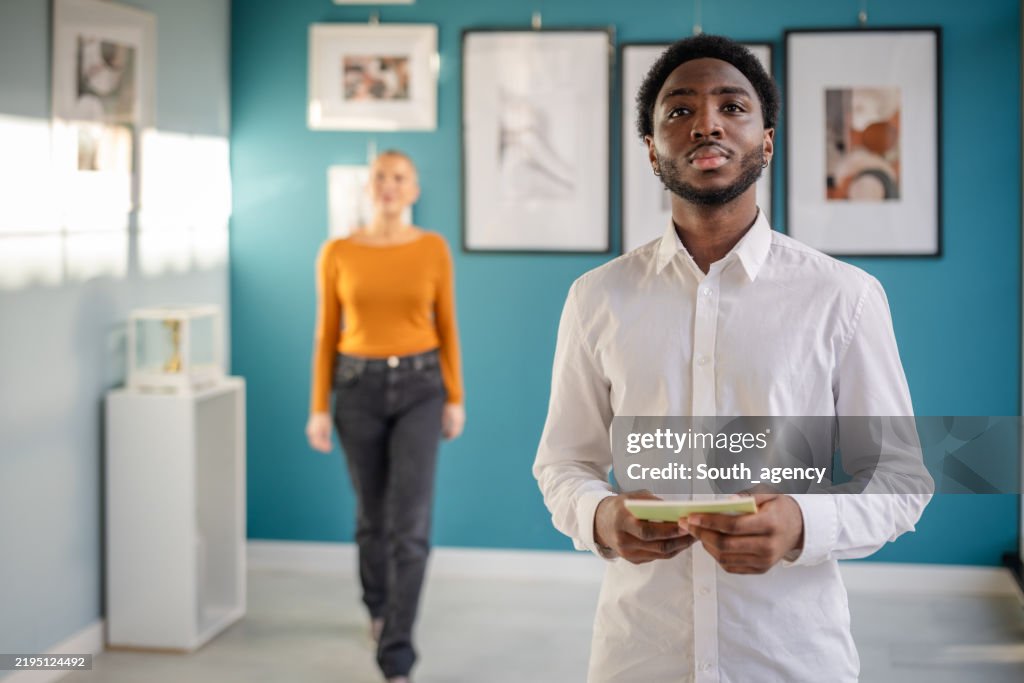 Art enthusiasts explore contemporary works at an exhibition in a bright gallery setting